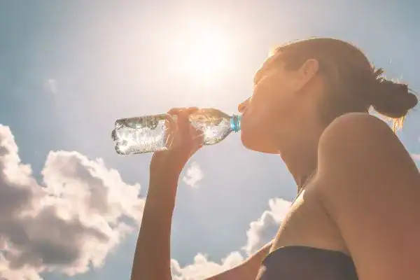 Hydration: The Secret Ingredient for a Toned Stomach and Enhanced Fitness 3 Image of woman drinking water to hydrate Livingston after run.