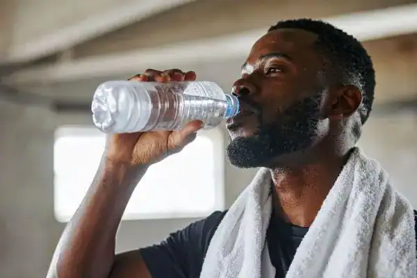 Image of man drinking water to improve hydration Livingston after work out.